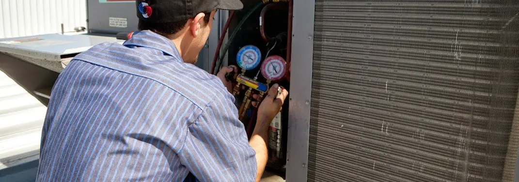 HVAC technician servicing a condenser unit in New Port Richey East